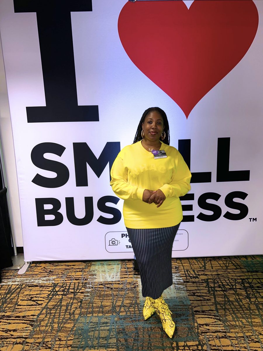 Adebukola Ajao in yellow in front of an I love small business backdrop